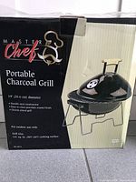 Photo showing front and side of the boxed portable charcoal grill with brand and product details visible.
