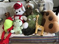 Photo showing nine different large stuffed toys arranged on a white couch including animals and characters.