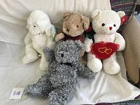 Group photo showing four Hart brand stuffed teddy bears including a white poodle, brown bear, white bear holding heart, and grey curly bear