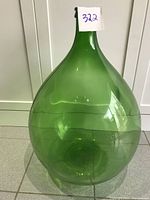 Front view of large green glass carboy wine jar showing full rounded body and narrow neck.