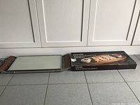 Electric warmer tray laid out on floor alongside its original box, showing Dansk branding and product details.