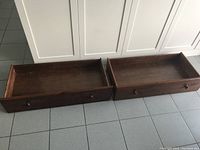 Two wooden drawers placed on tiled floor, showing overall items in lot