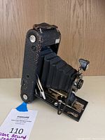 Side view of the antique Kodak folding bellows camera showing textured leatherette body, bellows extended, and metal hardware with some wear.