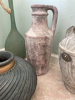 Close-up image of the tall beige ceramic jug with handle and distressed finish.