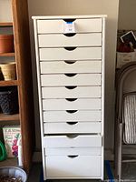Front view showing ten drawers with curved hand cutouts, white painted wood cabinet, blue lot tag on top drawer.