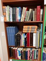 Three shelves of religious themed books in varying conditions including bibles, devotional and history books, some with worn spines and covers.