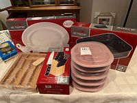 Full view of all items: cutlery set in box, wooden drawer organizer wrapped in plastic, stack of 5 Rubbermaid containers with lids, boxed roasting pan, and boxed white oval platter.