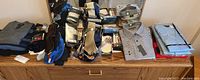 Various men's button down dress shirts in packaging and folded on dresser, plus stacks of men's socks in packaging.