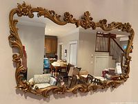 Front view showing the entire mirror with its ornate gold frame and detailed scrollwork.