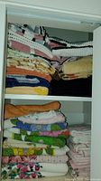 Photo showing stacked assortment of towels on shelf with floral and plain designs in various colors