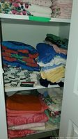 View of top and bottom shelves showing stacked towels in various colors and patterns including floral, solid, and checked designs.