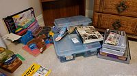 Wide view showing assortment of toys, craft supplies, plush toys, bead organizers, and art supply sets on the floor and furniture.