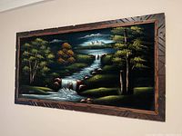 Frontal angled view of the signed oil on velvet painting showing the wooded river landscape and carved frame.