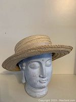 Side view of straw hat with wide flat brim and fabric band
