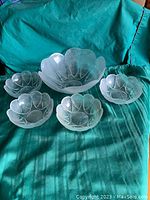 Five frosted glass salad bowls displayed on green fabric; one larger bowl with four smaller matching bowls arranged in front
