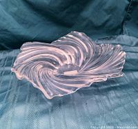 Angle view of the clear swirled glass bowl showing its heavy and smooth flowing swirl pattern with curved edges.