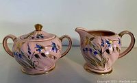 Photo of MCM Sadler creamer and covered sugar bowl set, showing pink base, blue flowers, and gold trim on both pieces.
