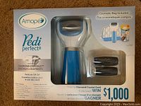Front view of Amipe Pedi Perfect pedicure gift set showing the pedicure device in blue and white, replacement roller heads, and cosmetic bag in original sealed box.