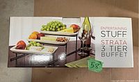 Box showing the product name and image of three-tier buffet set with rectangular ceramic platters and metal stand, with fruit and wine glasses on display.