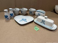 Photo showing entire set of ceramic tableware items with blue heart design including shakers, creamers, dishes, butter dish, and napkin holder.