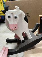 Close-up of the white and black wooden rocking cow showing paint and moving parts