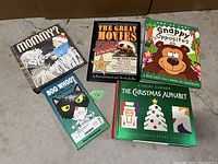 Photo of the five pop-up books closed and arranged on a floor, showing front covers and titles.