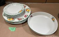 Stack of plates and bowls showing fruit and trellis pattern on white stoneware