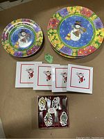 Photo of colorful round melamine plates with snowman design, square Santa Claus plates, and boxed set of small decorative melamine holiday items.
