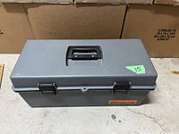 Closed gray plastic toolbox with black handle and Benchmark branding visible on front.