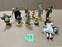 Full lot showing all Wizard of Oz figurines and Dorothy doll with basket on cardboard surface