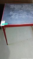 Photo showing black surface of vintage card table with scratches and red trim on the side