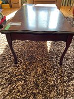 Front view of wood coffee table showing dark finish, cabriole legs, and curved edge design