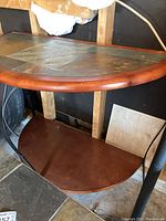 Side and bottom view of console table showing wood shelf beneath ceramic slate top and metal curved supports.