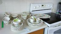 Dishes arranged on counter including plates, cups, saucers, and egg cups with floral patterns.