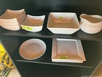 Top shelf with white square dishes including plates and bowls arranged, noting the different sizes and shapes.