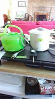 Photo showing the Black & Decker electric griddle in black with attached power cord and temperature dial alongside two electric tea kettles, one green translucent (Toastmaster) and one white (Toastess).