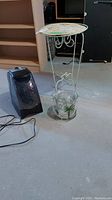 Photo showing humidifier, metal-legged round table with floral top, and clear plastic ice bucket with palm tree design.