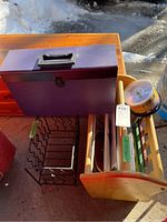 Photo showing wood magazine rack with books, blank DVDs, metal wire rack, and purple file box outdoors in sunlight