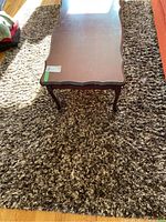 Full view of two tone shag carpet rug with wooden coffee table on top, showing size and texture.