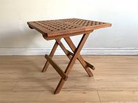Full view of the folding teak side table showing lattice top and folding legs.