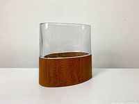 Front view of lucite and teak veneer vase showing smooth clear lucite and polished teak base.