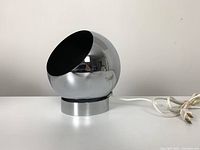 Side angled view showing the shape, chrome finish, and power cord on a short cylindrical base.