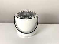White mid century modern ice bucket with black handle and starburst clear lucite lid.