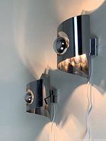 Two chrome-plated curved metal wall lamps illuminated on wall