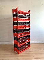Profile side view of the stacked wine racks showing alternating brown and red plastic sections with wavy bottle slots.