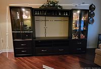 Front view of assembled entertainment unit showing two side cabinets, central shelving, drawers, and upper shelf with measurement callouts