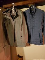 Green TanJay spring coat and Blue Wind River lightweight jacket hanging side by side