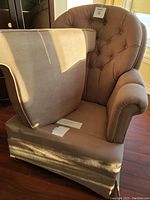 Light grey swivel rocking chair with loose cushion leaning against backrest, showing fabric texture and cushion details.