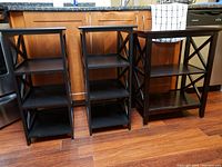 Front view of three black wooden shelving units showing size difference and shelf count