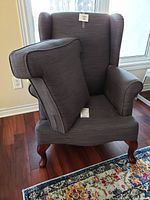 Front view of gray wingback chair with one arm cushion resting on seat.